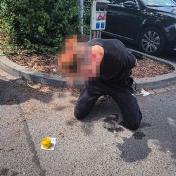 Zdrogovaný muž s ředidlem v ruce před obchodním centrem
